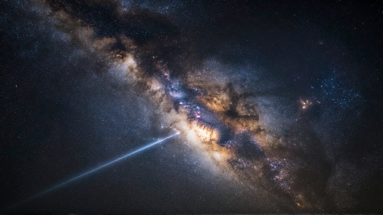 Vasta galaxia espiral con nubes de polvo cósmico azul y dorado y un haz de luz brillante.