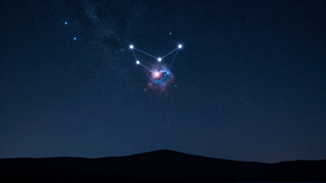 Constelación de Orión brillando en un cielo nocturno sobre la silueta de montañas oscuras.